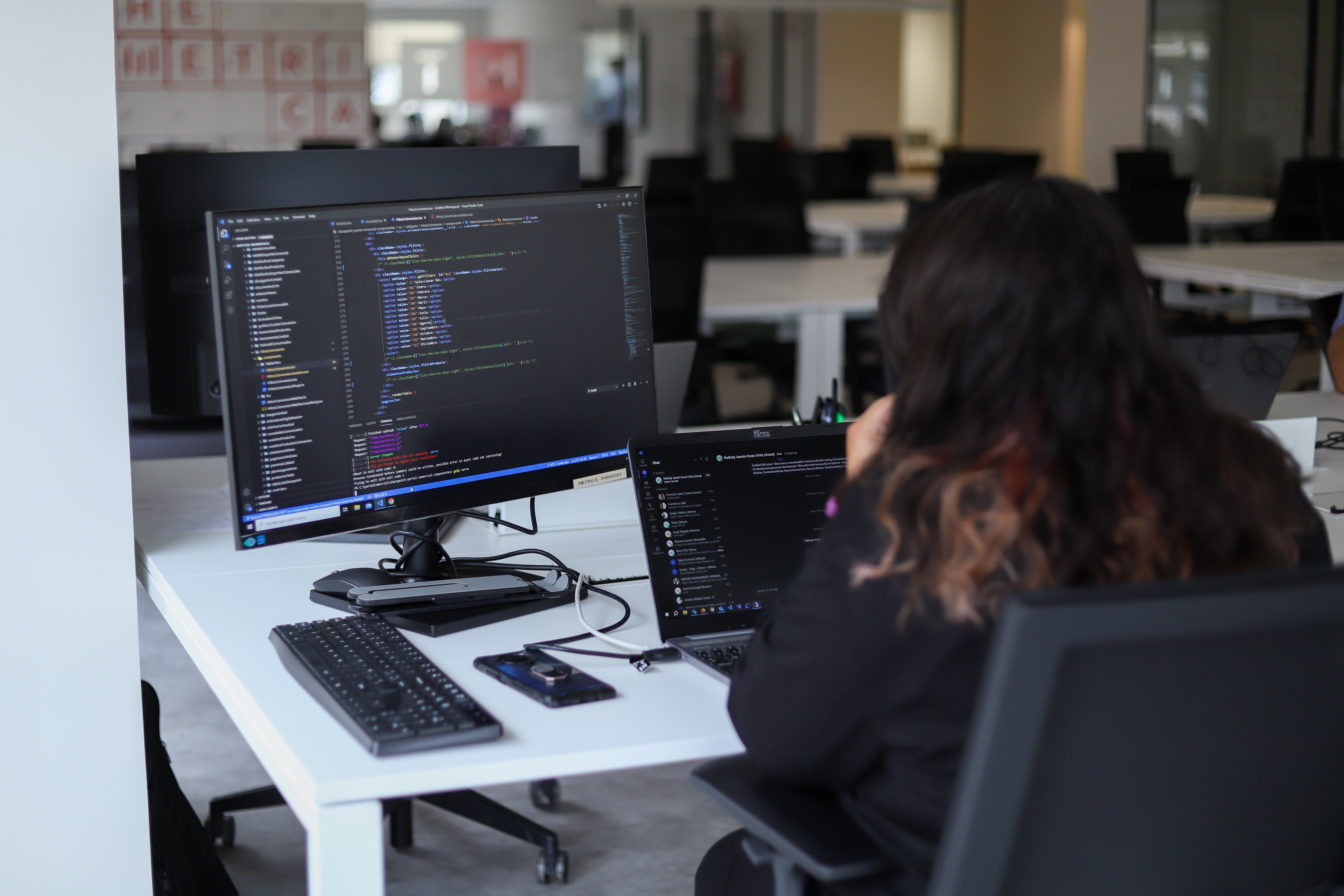 Desarrolladora revisando código en dos monitores